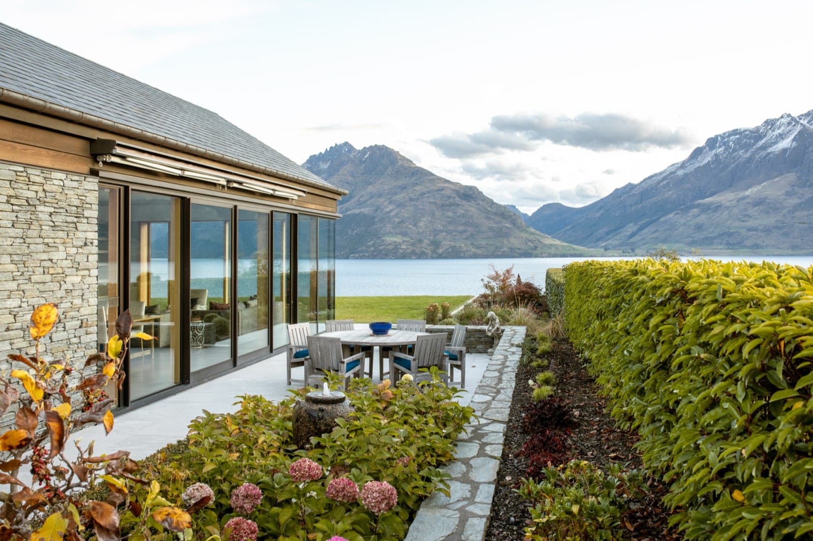 The terrace at Drift Bay Lakefront, with clipped hedging, hydrangeas and the lake and mountains beyond