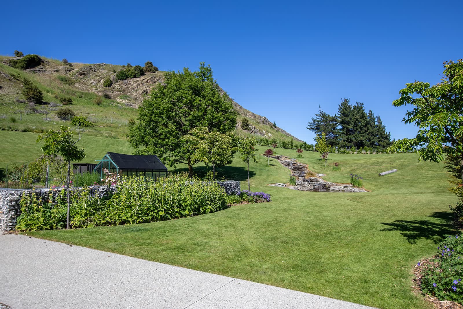 The garden at Hogan's Gully Haven, with its lawn, planted terraces and rock water feature below the hillside