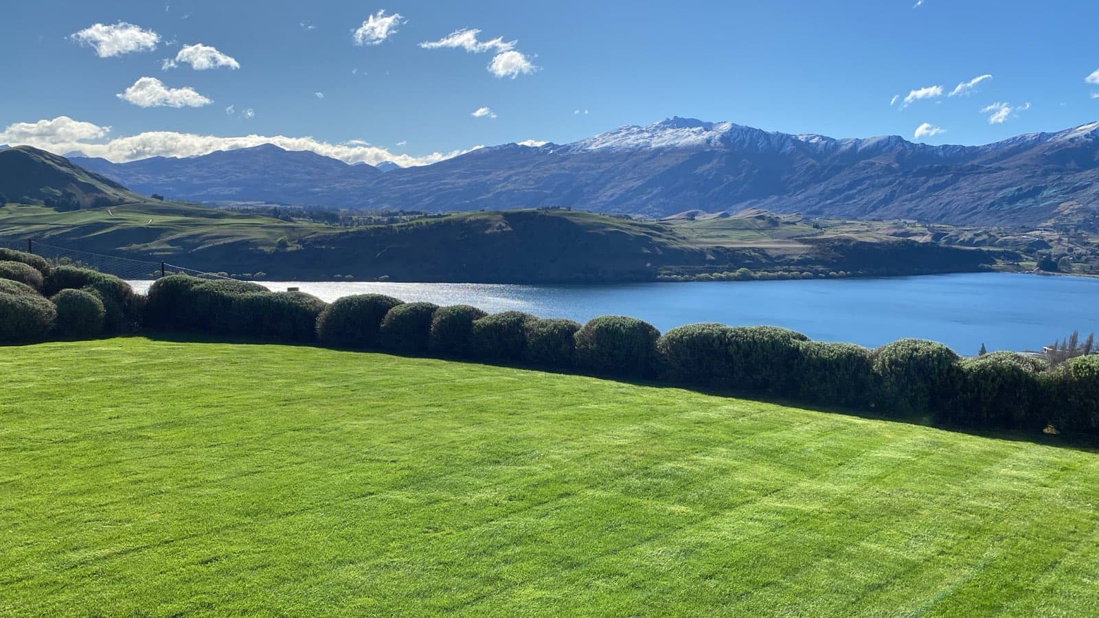A Diva-kept lawn running out to a clipped hedge line, the lake and the snow-topped range beyond