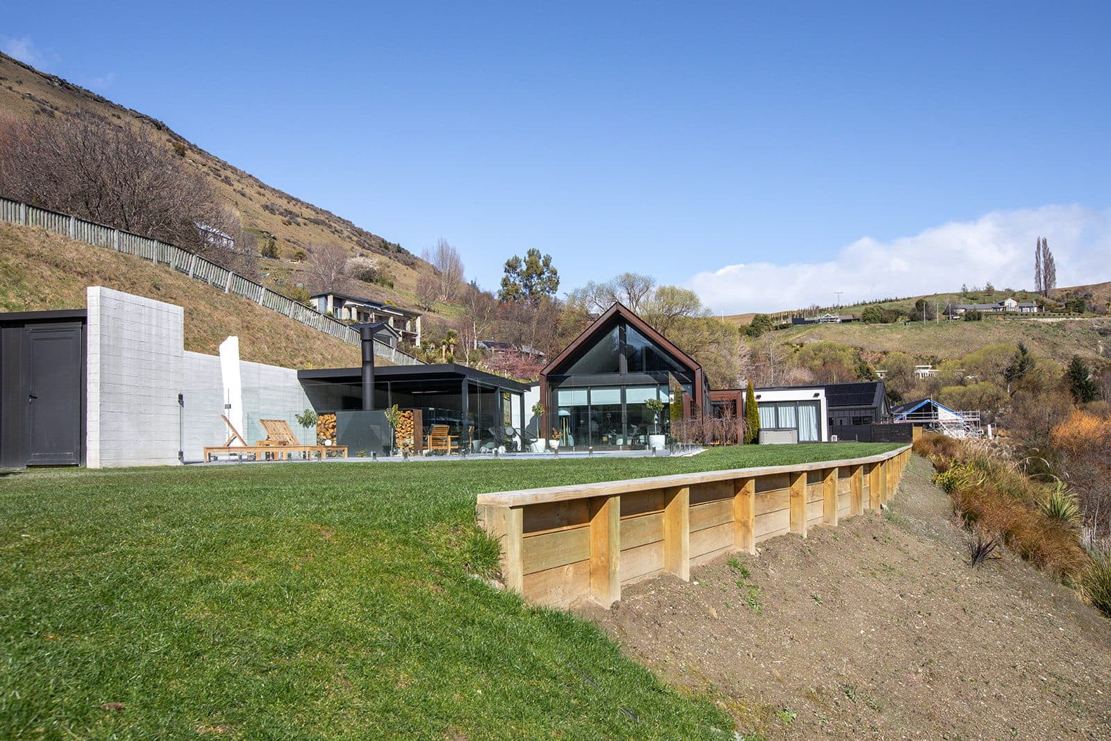 A timber retaining wall holding a level lawn above a sloping bank