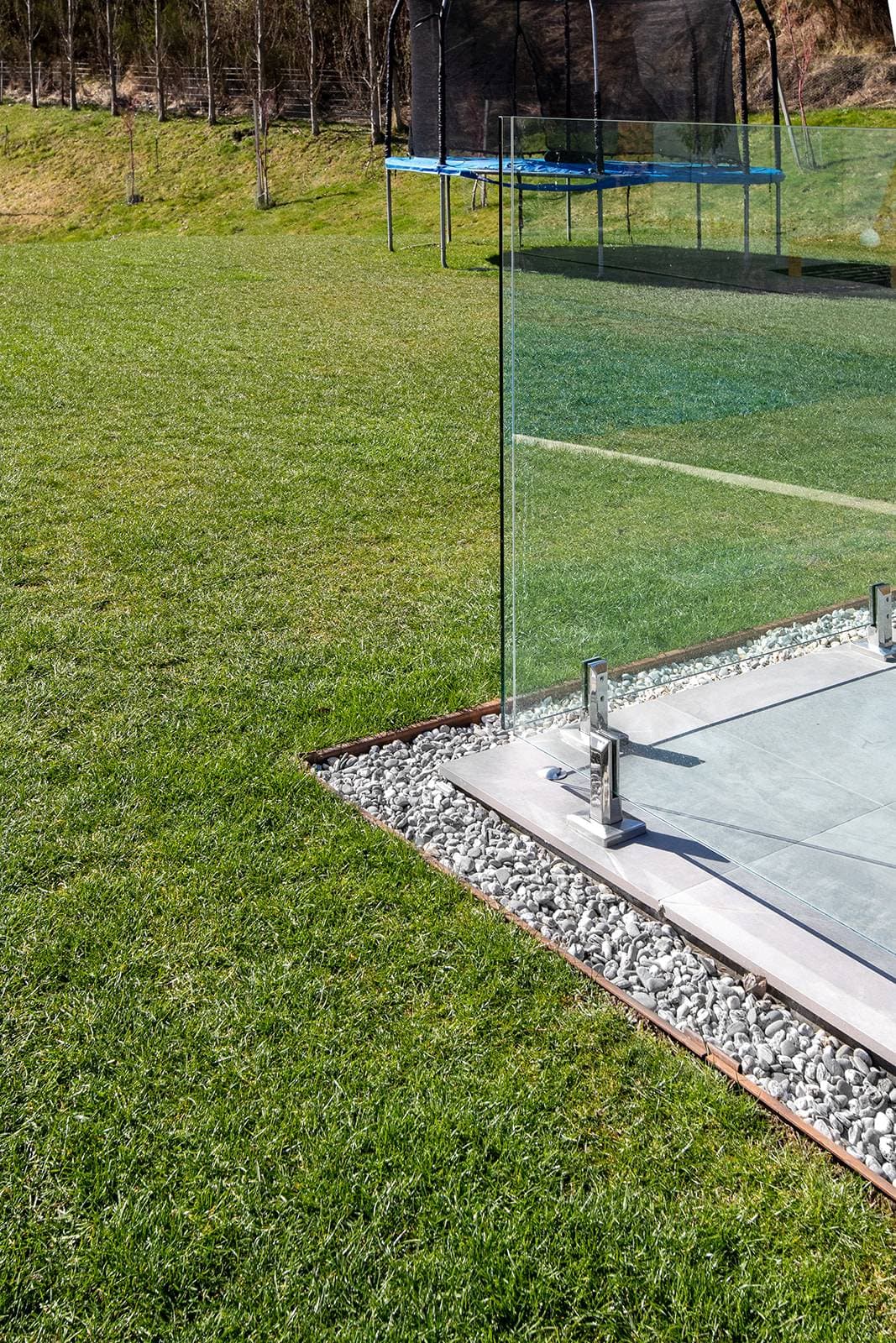 Steel edging between lawn and a gravel strip beside a paved terrace